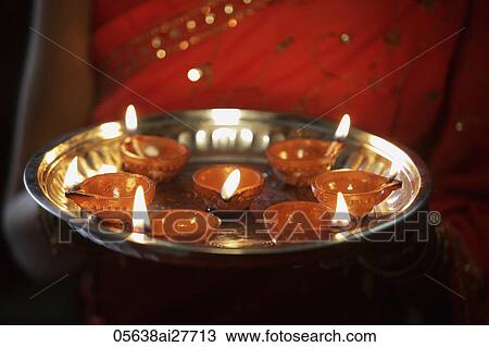 Cropped shot of woman holding a silver tray of oil lamps. View Large Photo Image Stock Image - Cropped shot of woman holding a silver tray of oil lamps.. Fotosearch