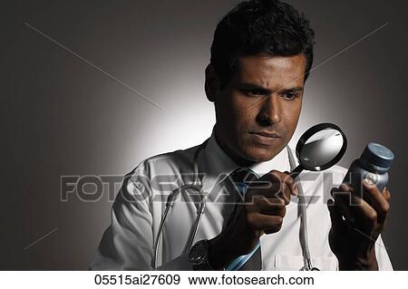 Doctor looking at bottle with magnifying glass View Large Photo Image Stock Photo - Doctor looking at bottle with magnifying glass. Fotosearch