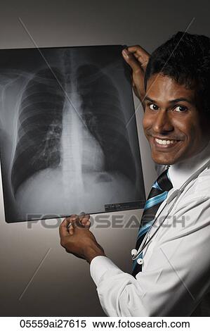 Doctor looking at X ray and smiling View Large Photo Image Stock Photography - Doctor looking at X ray and smiling. Fotosearch