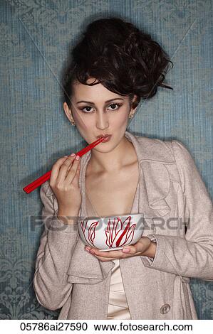 Head shot of Asian woman eating with red chopsticks View Large Photo Image Stock Image - Head shot of Asian woman eating with red chopsticks. Fotosearch