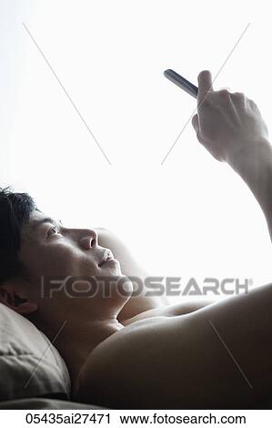 head shot of Chinese man laying on bed looking at phone View Large Photo Image Stock Image - head shot of Chinese man laying on bed looking at phone. Fotosearch