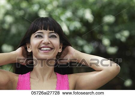 Stock Photo - Head shot of smiling woman with hands in her hair. Fotosearch