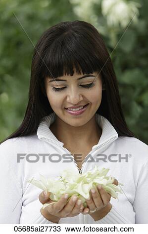 Stock Image - Head shot of woman looking at flowers in her hands. Fotosearch