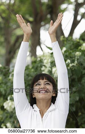 Stock Photograph - Head shot of woman smiling with arms outstretched overhead. Fotosearch
