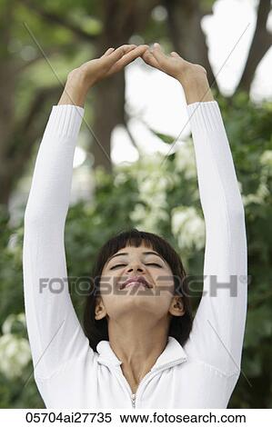 Stock Photography - Head shot of woman stretching with arms over head. Fotosearch
