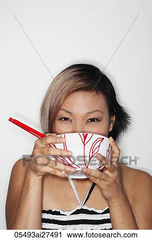 Head shot of young woman holding bowl to her mouth View Large Photo Image Stock Image - Head shot of young woman holding bowl to her mouth. Fotosearch