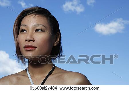 Head shot of young woman looking up with blue sky background View Large Photo Image Picture - Head shot of young woman looking up with blue sky background. Fotosearch