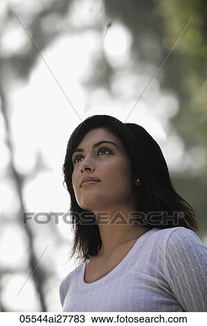 Stock Image - Head shot of young woman looking up to the sky. Fotosearch