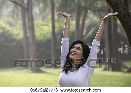 Head shot of young woman smiling with arms raised over head View Large Photo Image Stock Photograph - Head shot of young woman smiling with arms raised over head. Fotosearch