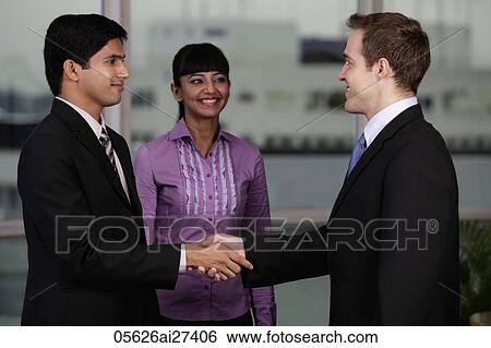 Indian and Caucasian man shaking hands while woman looks on. View Large Photo Image Stock Photograph - Indian and Caucasian man shaking hands while woman looks on.. Fotosearch