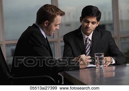 Stock Photo - Indian man and Caucasian men discussing a document. Fotosearch