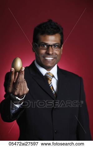Indian man holding golden egg and smiling View Large Photo Image Stock Photo - Indian man holding golden egg and smiling. Fotosearch