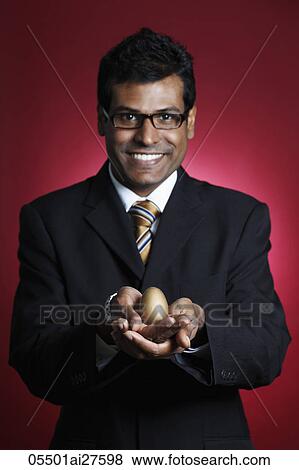 Indian man holding golden egg in his hands View Large Photo Image Stock Photo - Indian man holding golden egg in his hands. Fotosearch