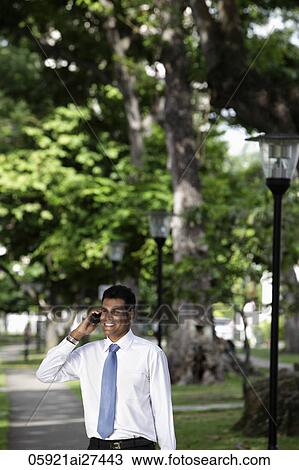Indian man talking on phone under trees View Large Photo Image Stock Image - Indian man talking on phone under trees. Fotosearch
