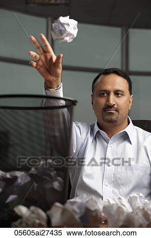 Stock Photography - Indian man throwing crumples paper into wasted basket. Fotosearch