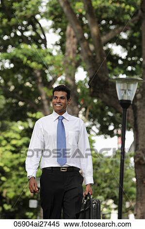 Indian man walking outside holding briefcase and smiling View Large Photo Image Stock Photography - Indian man walking outside holding briefcase and smiling. Fotosearch
