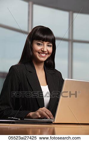 Indian woman smiling and working on laptop View Large Photo Image Stock Photography - Indian woman smiling and working on laptop. Fotosearch