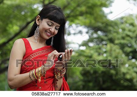 Stock Photo - Indian woman texting on phone, outdoors. Fotosearch