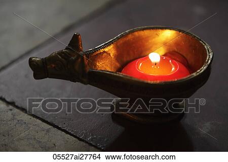 Picture - Lit candle in bronze cow dish. Fotosearch