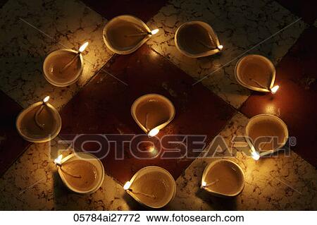 Stock Image - Lit clay oil lamps in a circle. Fotosearch