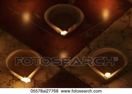 Stock Photo - Lit clay oil lamps on floor. Fotosearch
