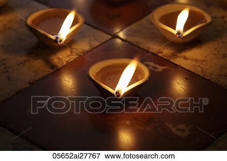 Stock Photo - Lit clay oil lamps on floor. Fotosearch