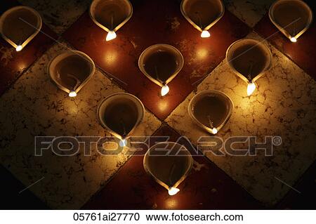 Stock Image - Lit oil lamps on tile. Fotosearch