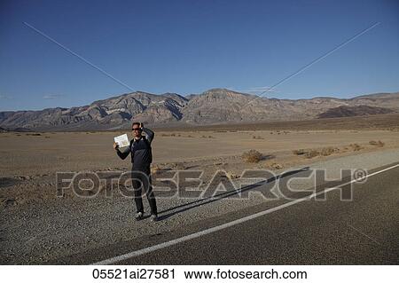 Man holding map on the side of the road in the desert View Large Photo Image Stock Image - Man holding map on the side of the road in the desert. Fotosearch