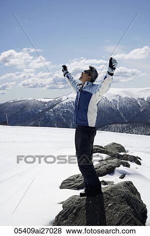 Man standing on snow covered mountain with arms up View Large Photo Image Stock Photo - Man standing on snow covered mountain with arms up. Fotosearch