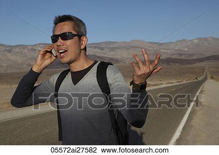 Man talking on phone on the side of deserted road View Large Photo Image Stock Image - Man talking on phone on the side of deserted road. Fotosearch