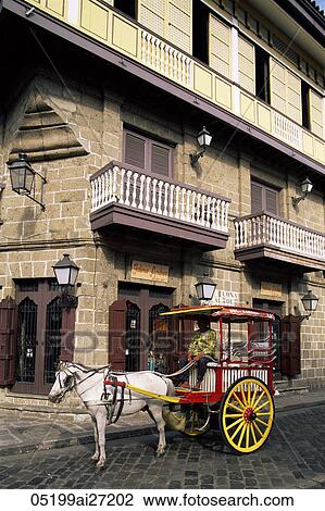 Stock Image - Philippines, Manila, Calesa or Horse-drawn Carriage and Spanish Colonial Building in the Intramuros Historical District. Fotosearch