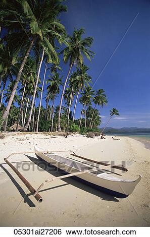 Stock Photograph - Philippines, Palawan, Bascuit Bay, El Nido, Couple Sunbathing on Beach with Outrigger Boat in Foreground. Fotosearch