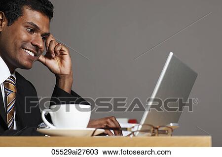 Stock Image - Profile shot of Indian man working on laptop. Fotosearch