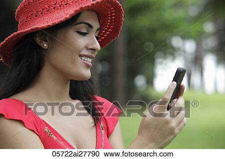 Profile shot of young woman wearing a red hat and looking at her phone. View Large Photo Image Stock Image - Profile shot of young woman wearing a red hat and looking at her phone.. Fotosearch