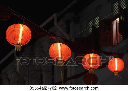 Stock Image - Red lanterns glowing at night above the street. Fotosearch