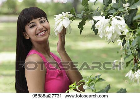 Smiling woman with long hair, holding flowers View Large Photo Image Stock Image - Smiling woman with long hair, holding flowers. Fotosearch