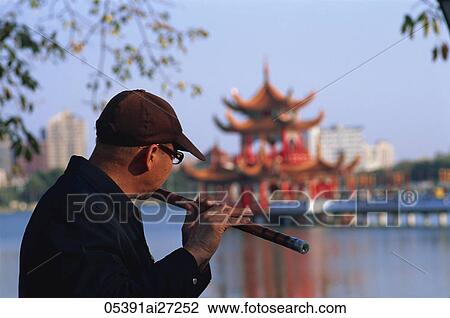 Stock Image - Taiwan, Kaohsiung, Man Playing Flute at Lotus Lake. Fotosearch