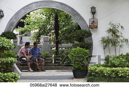 Stock Photo - Two men sit inside circular door of park. Hong Kong. Fotosearch