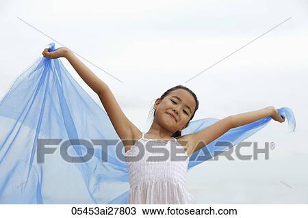 Stock Image - young girl holding blue cloth smiling. Fotosearch