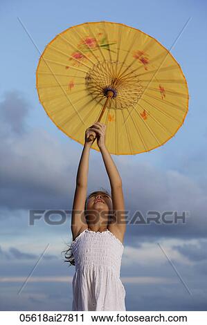 young girl holding up yellow Chinese umbrella, bluebsky background View Large Photo Image Stock Image - young girl holding up yellow Chinese umbrella, bluebsky background. Fotosearch