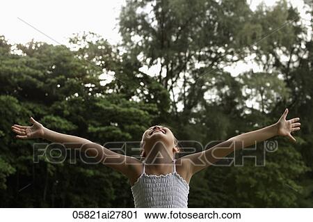 Young girl with arms outstretched looking up at the sky smiling, trees background View Large Photo Image Stock Image - Young girl with arms outstretched looking up at the sky smiling, trees background. Fotosearch