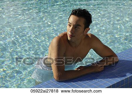 Stock Photo - Young man resting on side of swimming pool. Fotosearch