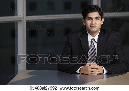 Young man sitting at table hands folded View Large Photo Image Stock Image - Young man sitting at table hands folded. Fotosearch