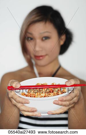 Young woman holding a bowl of pasta with red chopsticks, face out of focus View Large Photo Image Stock Image - Young woman holding a bowl of pasta with red chopsticks, face out of focus. Fotosearch
