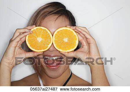 Young woman holding large orange slices over her eyes and laughing View Large Photo Image Stock Photo - Young woman holding large orange slices over her eyes and laughing. Fotosearch