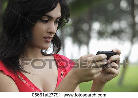 Young woman looking at phone outdoors View Large Photo Image Stock Image - Young woman looking at phone outdoors. Fotosearch