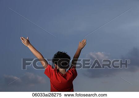 Stock Photography - back view of young boy with red shirt with arms outstretched. Fotosearch