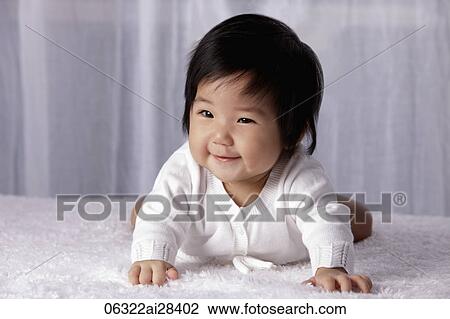 Stock Image - Chinese baby on tummy, smiling. Fotosearch