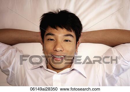 close up of man laying on bed with hands behind his head and smiling View Large Photo Image Stock Image - close up of man laying on bed with hands behind his head and smiling. Fotosearch