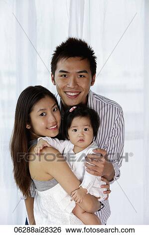 Stock Photograph - Father and mother holding baby and smiling. Fotosearch